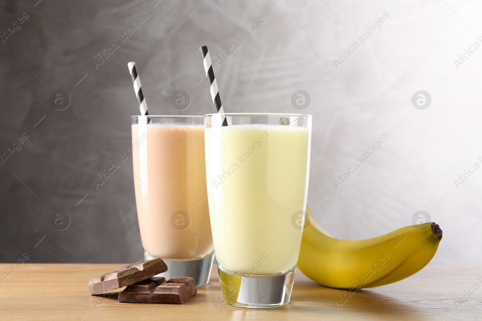 Tasty milkshakes in glasses and ingredients on wooden table Photo of Tasty milkshakes in glasses and ingredients on wooden table