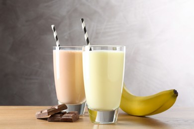 Photo of Tasty milkshakes in glasses and ingredients on wooden table