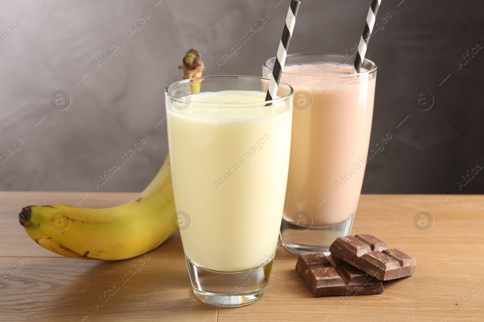 Tasty milkshakes in glasses and ingredients on wooden table Photo of Tasty milkshakes in glasses and ingredients on wooden table