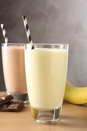 Photo of Tasty milkshakes in glasses and ingredients on wooden table, closeup
