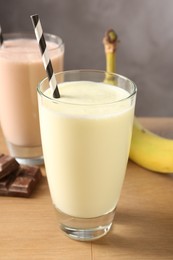 Photo of Tasty milkshakes in glasses and ingredients on wooden table, closeup
