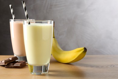 Photo of Tasty milkshakes in glasses and ingredients on wooden table, space for text
