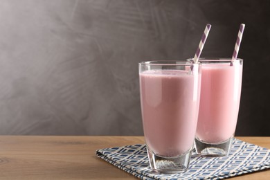 Photo of Tasty milkshakes in glasses on wooden table, space for text