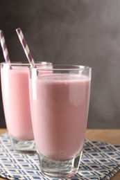 Photo of Tasty milkshakes in glasses on wooden table, closeup