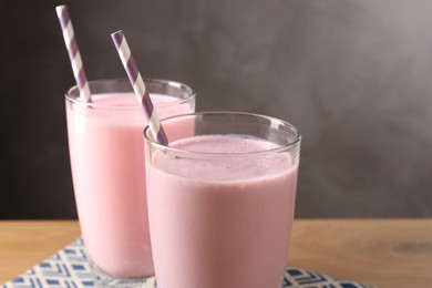 Photo of Tasty milkshakes in glasses on wooden table, closeup. Space for text