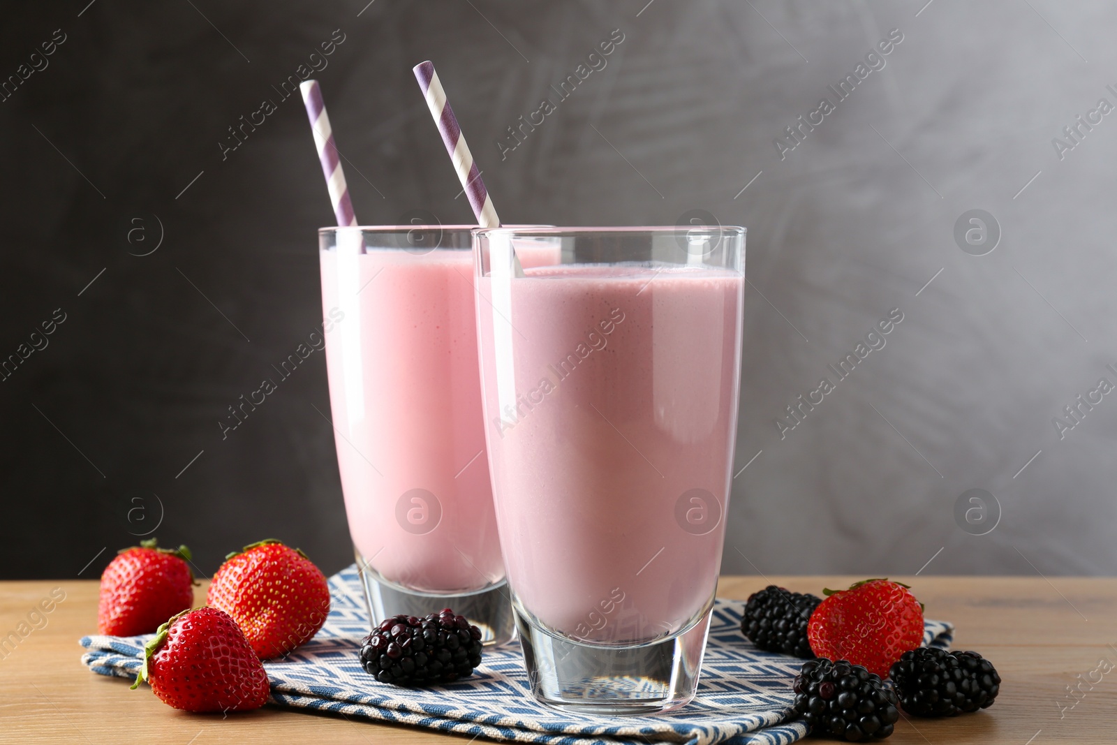 Photo of Tasty milkshakes in glasses and berries on wooden table