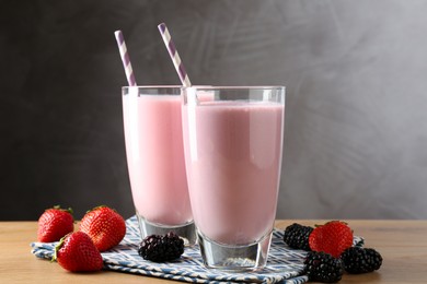Photo of Tasty milkshakes in glasses and berries on wooden table