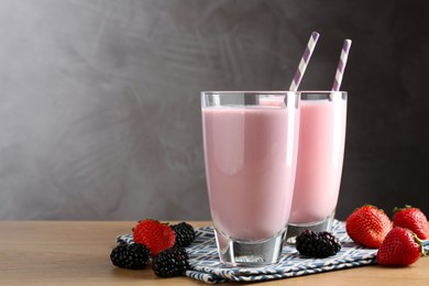 Photo of Tasty milkshakes in glasses and berries on wooden table, space for text