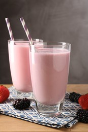 Photo of Tasty milkshakes in glasses and berries on wooden table, closeup