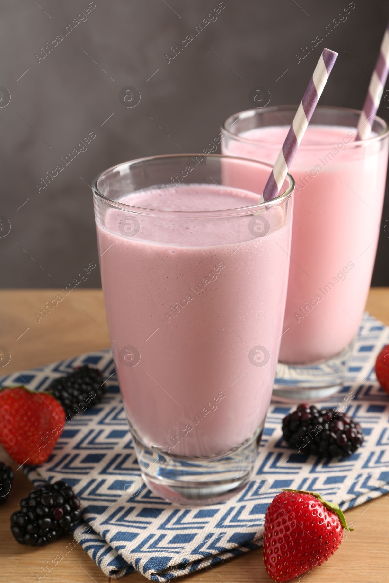 Photo of Tasty milkshakes in glasses and berries on wooden table, closeup