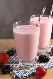 Photo of Tasty milkshakes in glasses and berries on wooden table, closeup