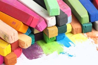 Photo of Many colorful chalk pastels on white background, closeup