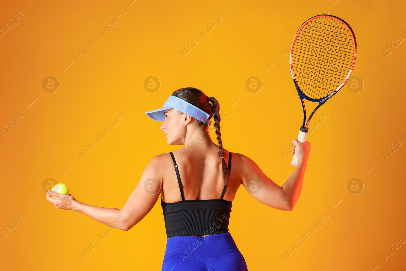 Woman with racket and tennis ball on orange background Photo of Woman with racket and tennis ball on orange background
