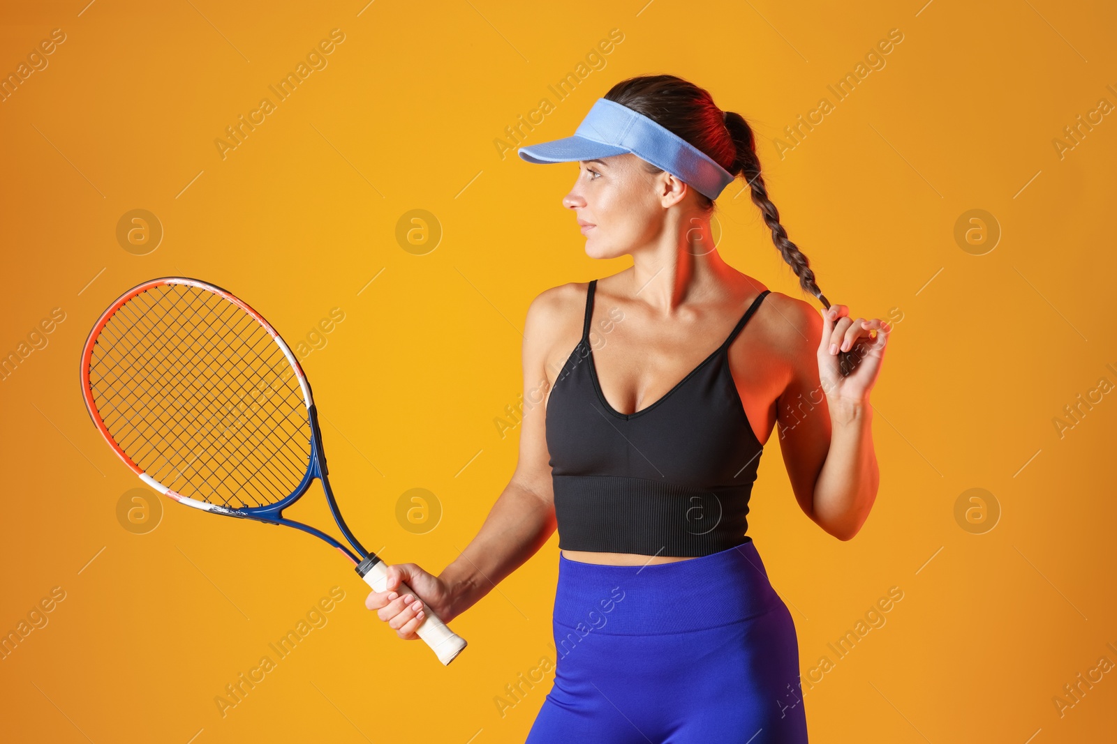 Woman with tennis racket on orange background Photo of Woman with tennis racket on orange background