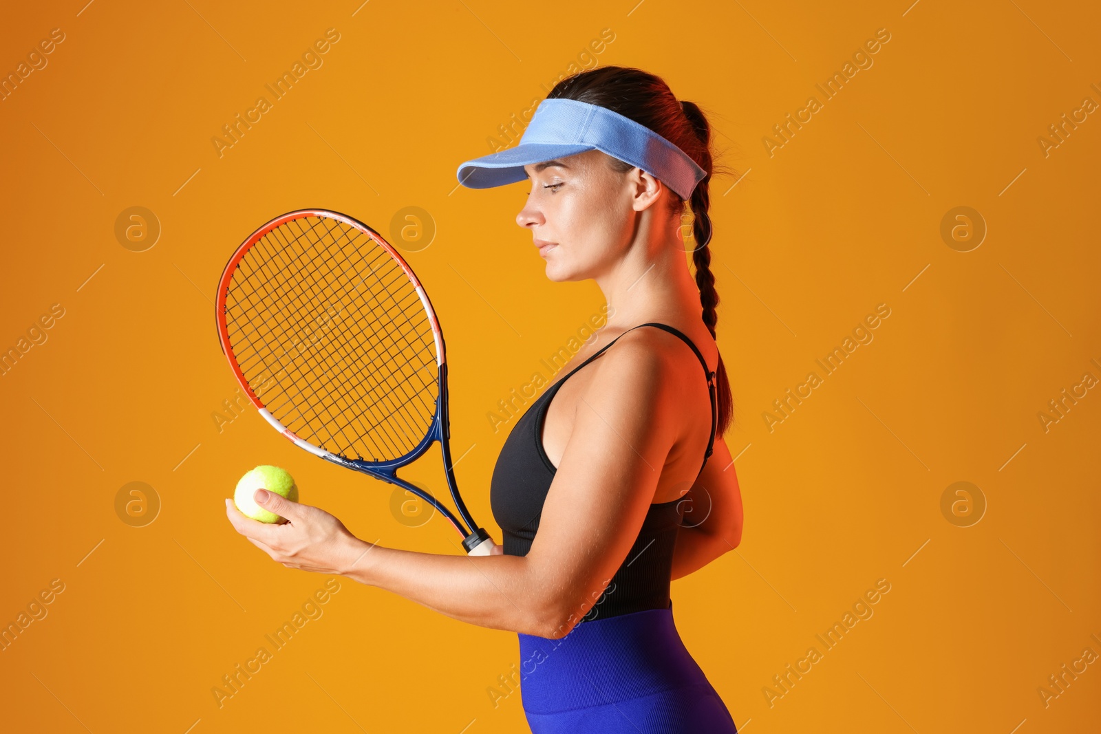 Woman with racket and tennis ball on orange background Photo of Woman with racket and tennis ball on orange background