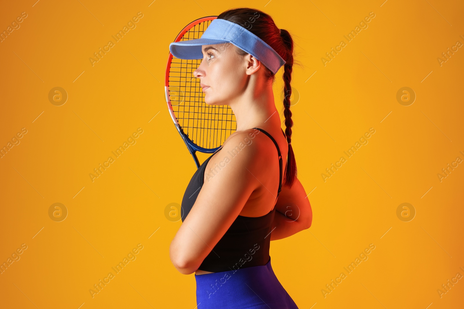 Woman with tennis racket on orange background Photo of Woman with tennis racket on orange background