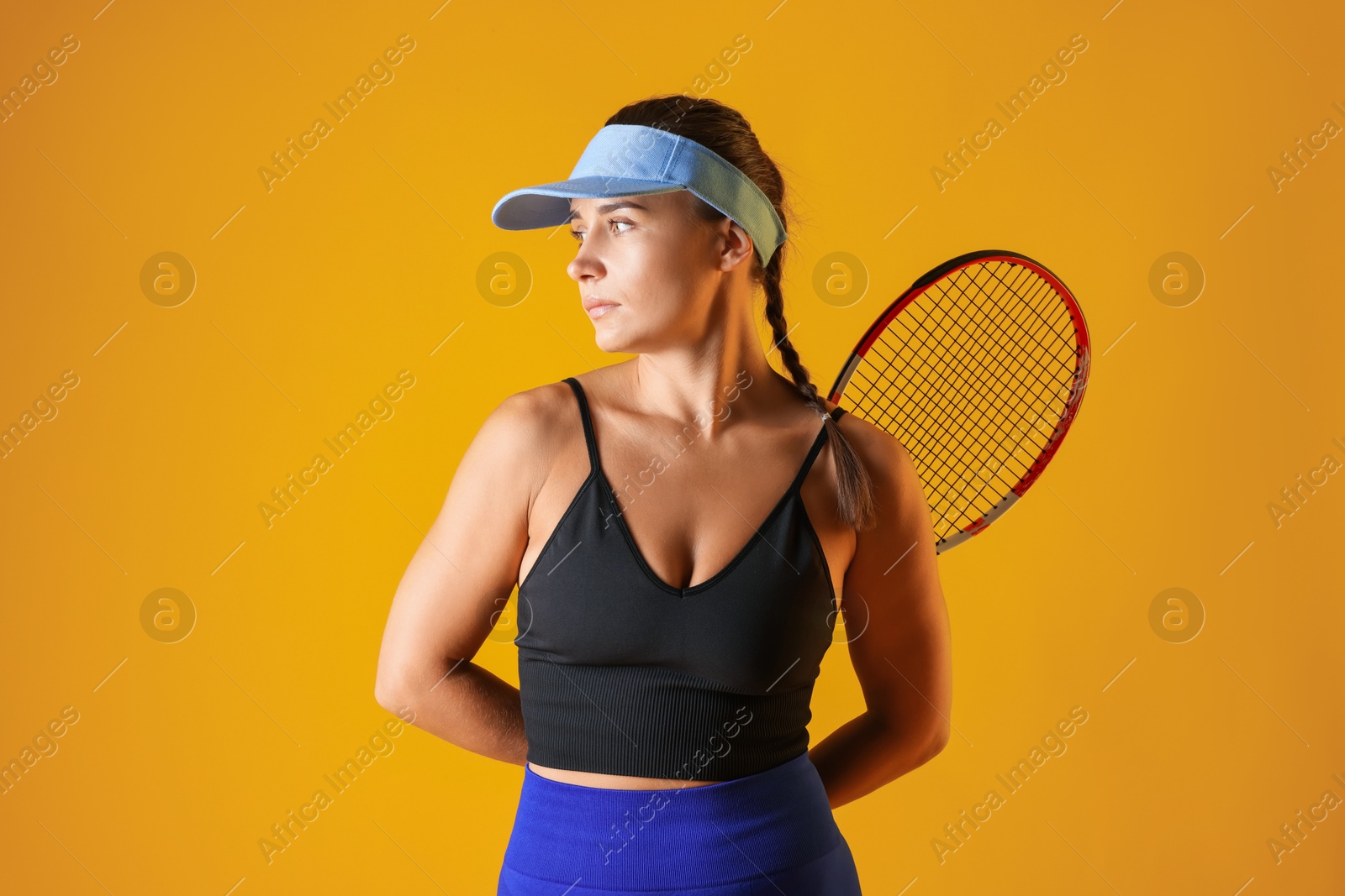 Woman with tennis racket on orange background Photo of Woman with tennis racket on orange background