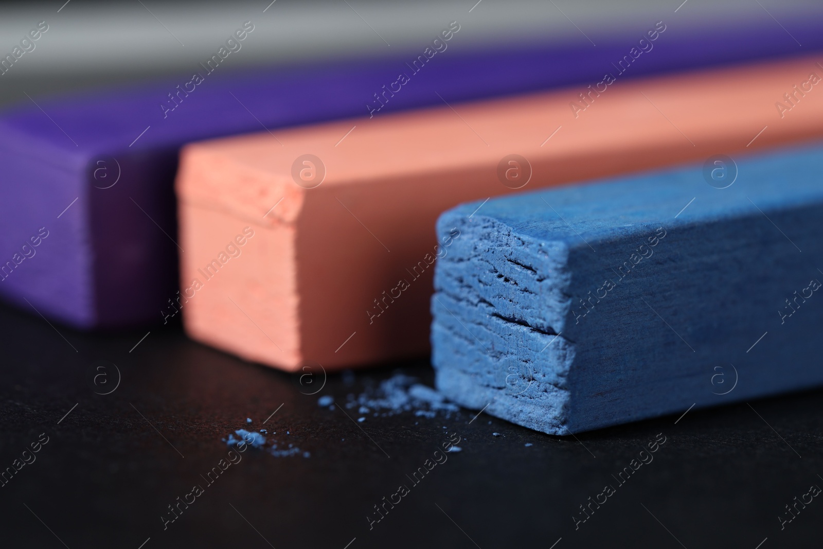Photo of Colorful chalk pastels on black background, closeup