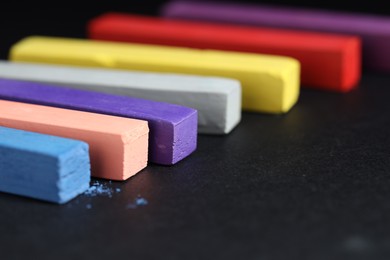Photo of Colorful chalk pastels on black background, closeup
