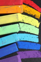 Photo of Colorful chalk pastels on black background, flat lay