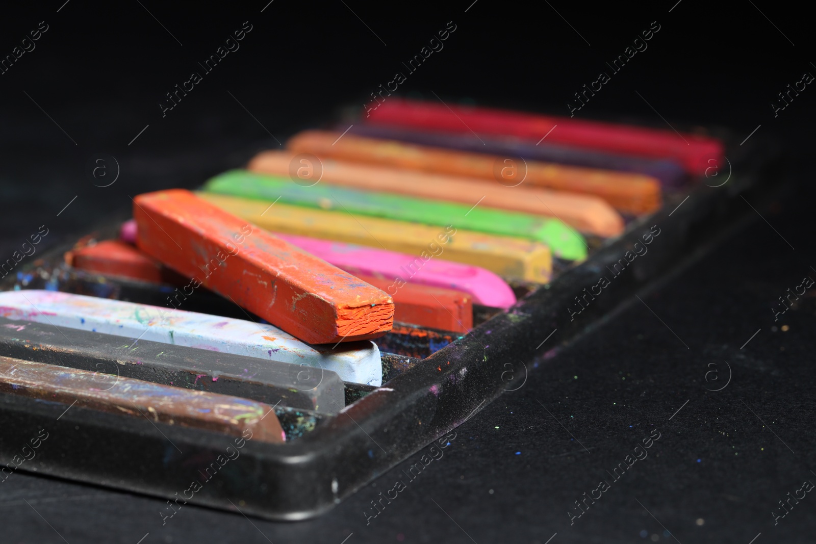 Photo of Set of colorful chalk pastels on black background, closeup