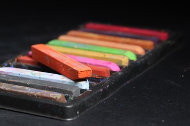 Photo of Set of colorful chalk pastels on black background, closeup