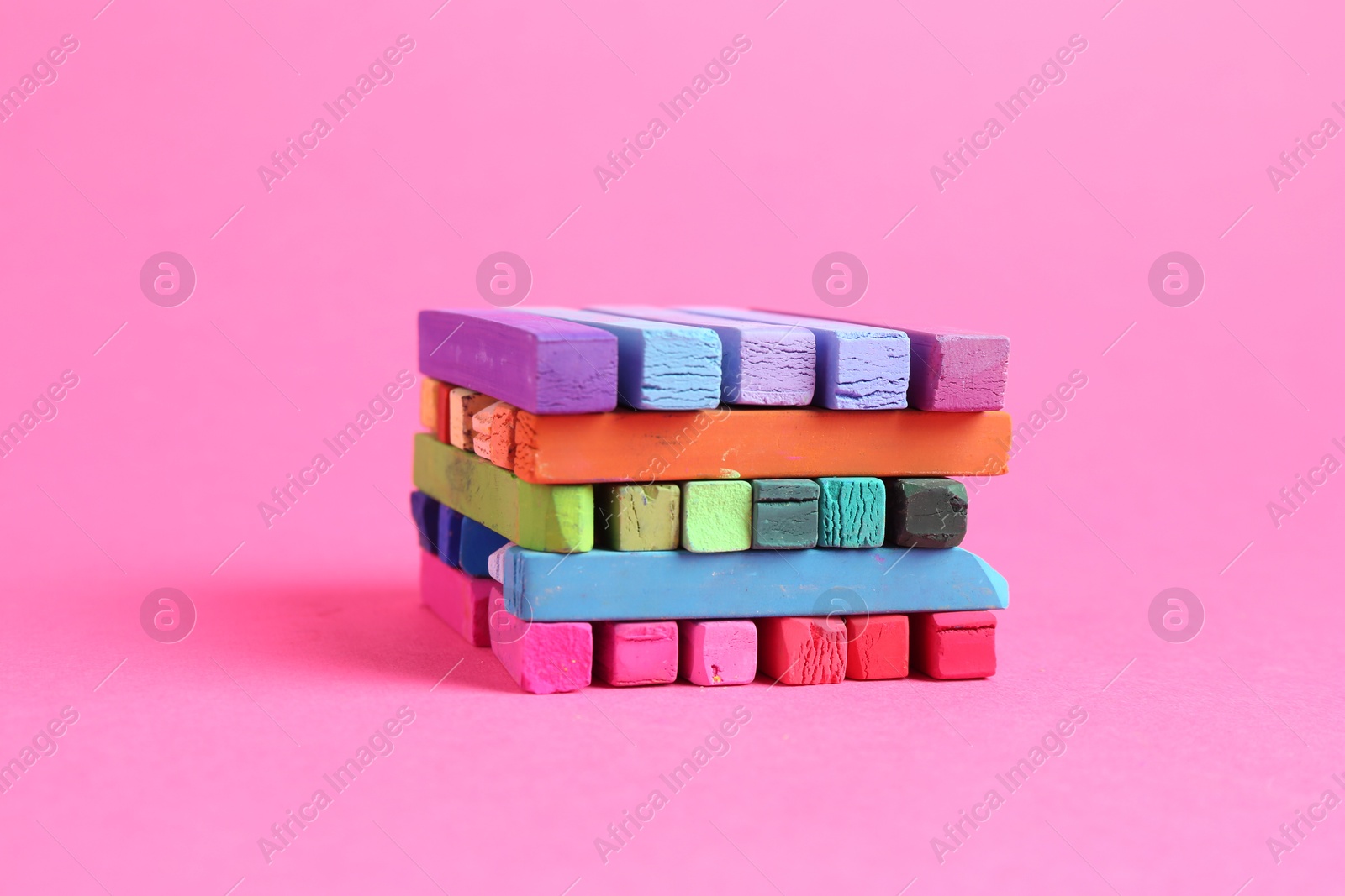 Many colorful chalk pastels on pink background Photo of Many colorful chalk pastels on pink background