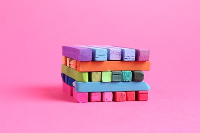 Photo of Many colorful chalk pastels on pink background