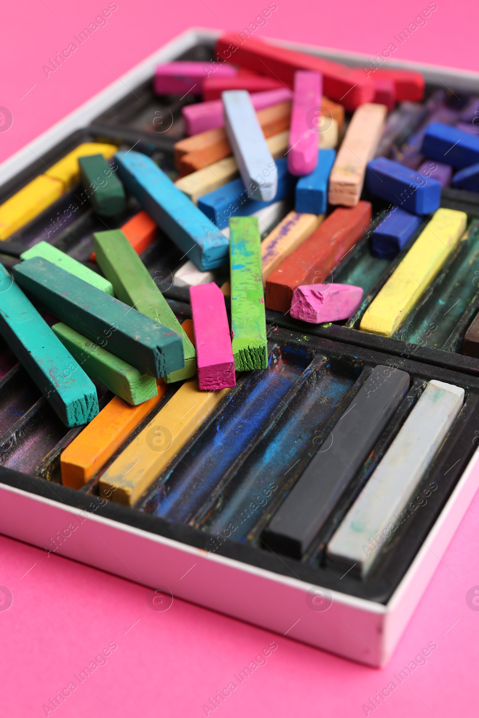 Photo of Set of colorful chalk pastels on pink background, closeup