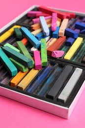 Photo of Set of colorful chalk pastels on pink background, closeup