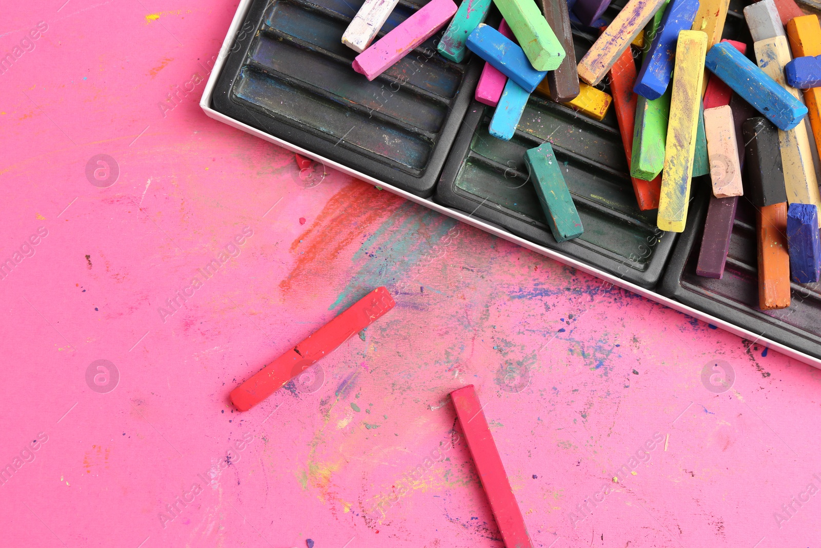 Photo of Many colorful chalk pastels on pink background, flat lay