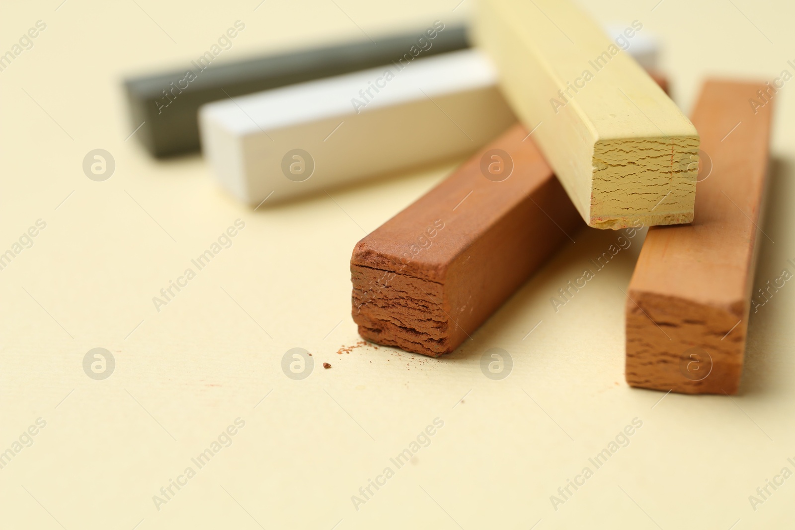 Photo of Many colorful chalk pastels on beige background, closeup. Space for text