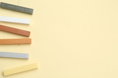 Photo of Many colorful chalk pastels on beige background, flat lay. Space for text