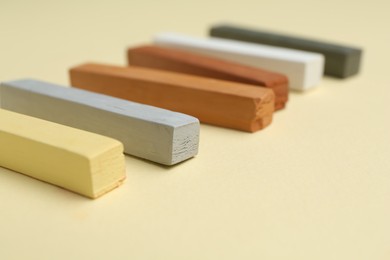 Photo of Many colorful chalk pastels on beige background, closeup