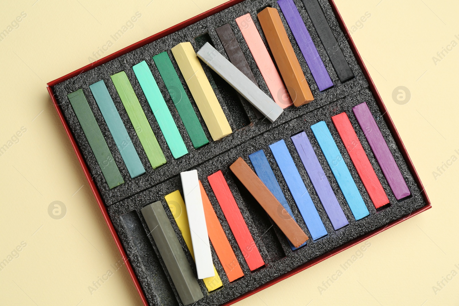 Photo of Set of colorful chalk pastels on beige background, top view