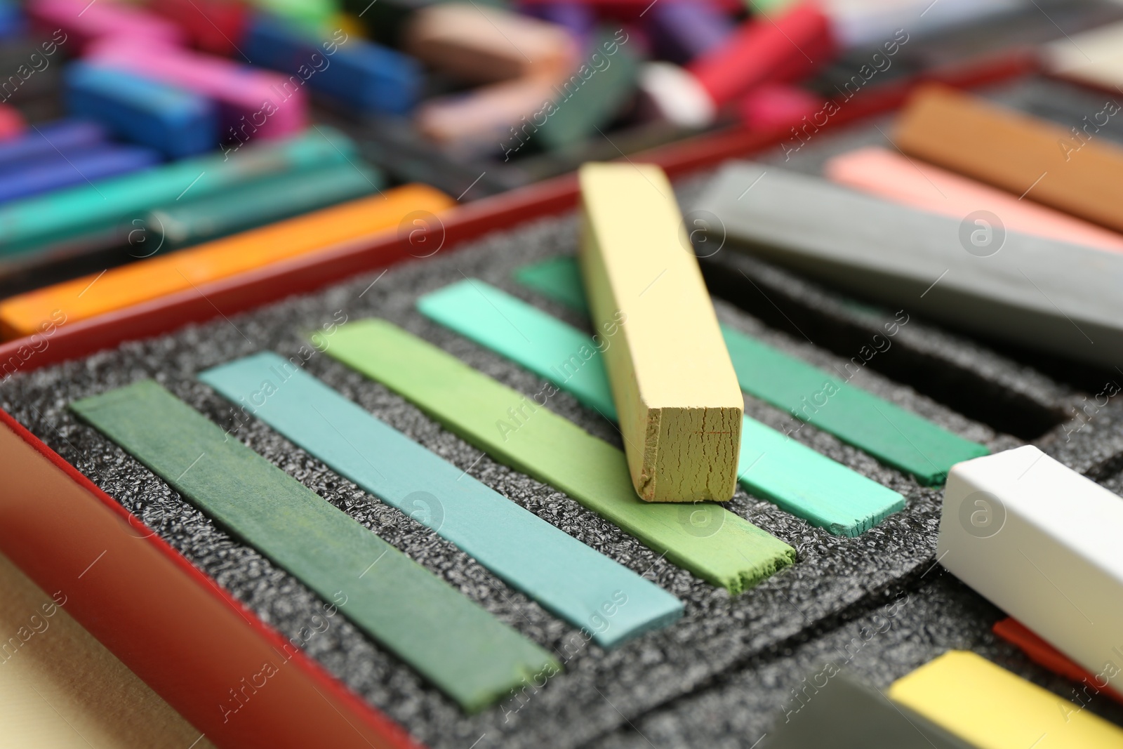 Photo of Set of colorful chalk pastels on beige background, closeup