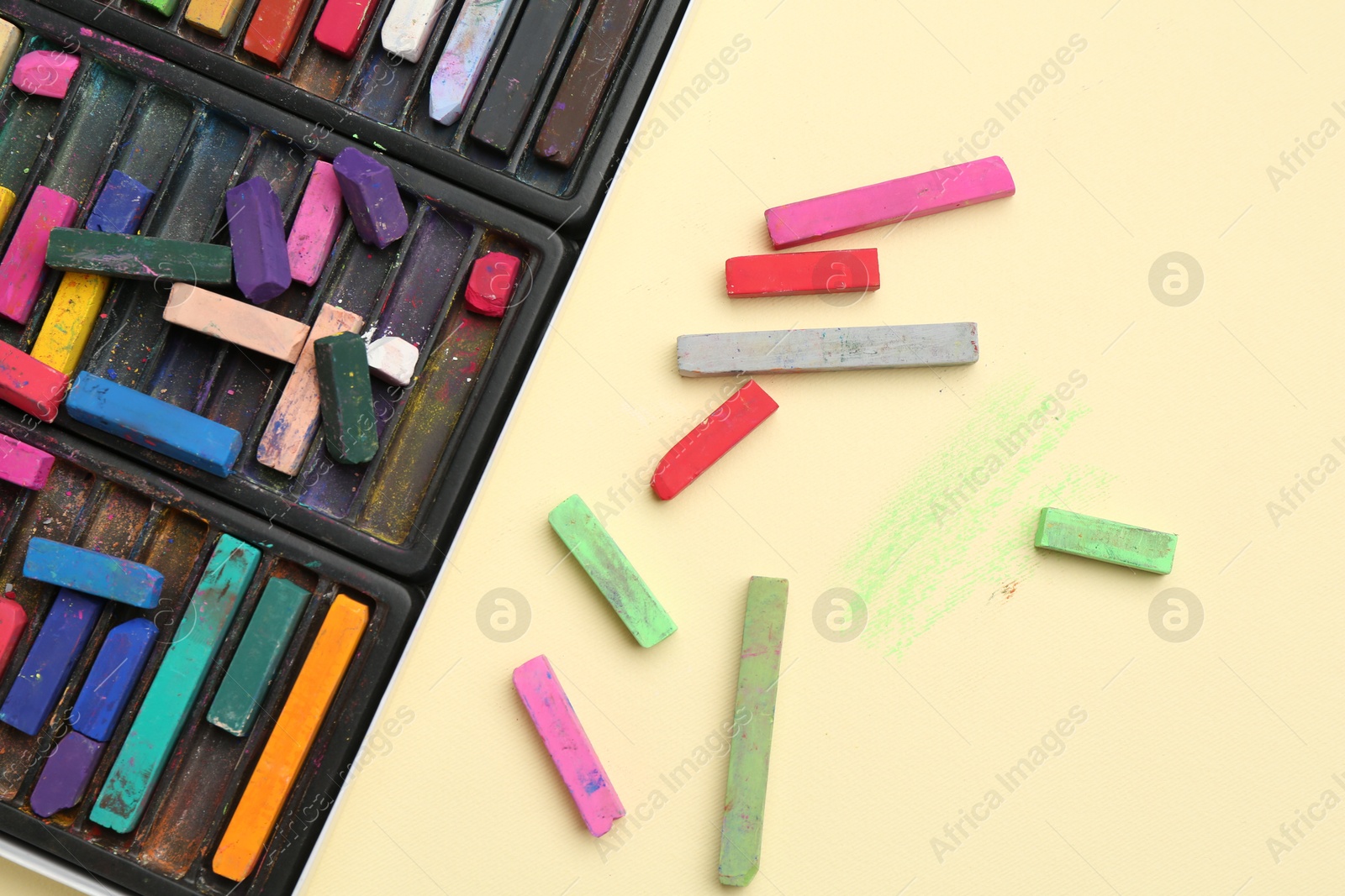 Photo of Many colorful chalk pastels on beige background, flat lay