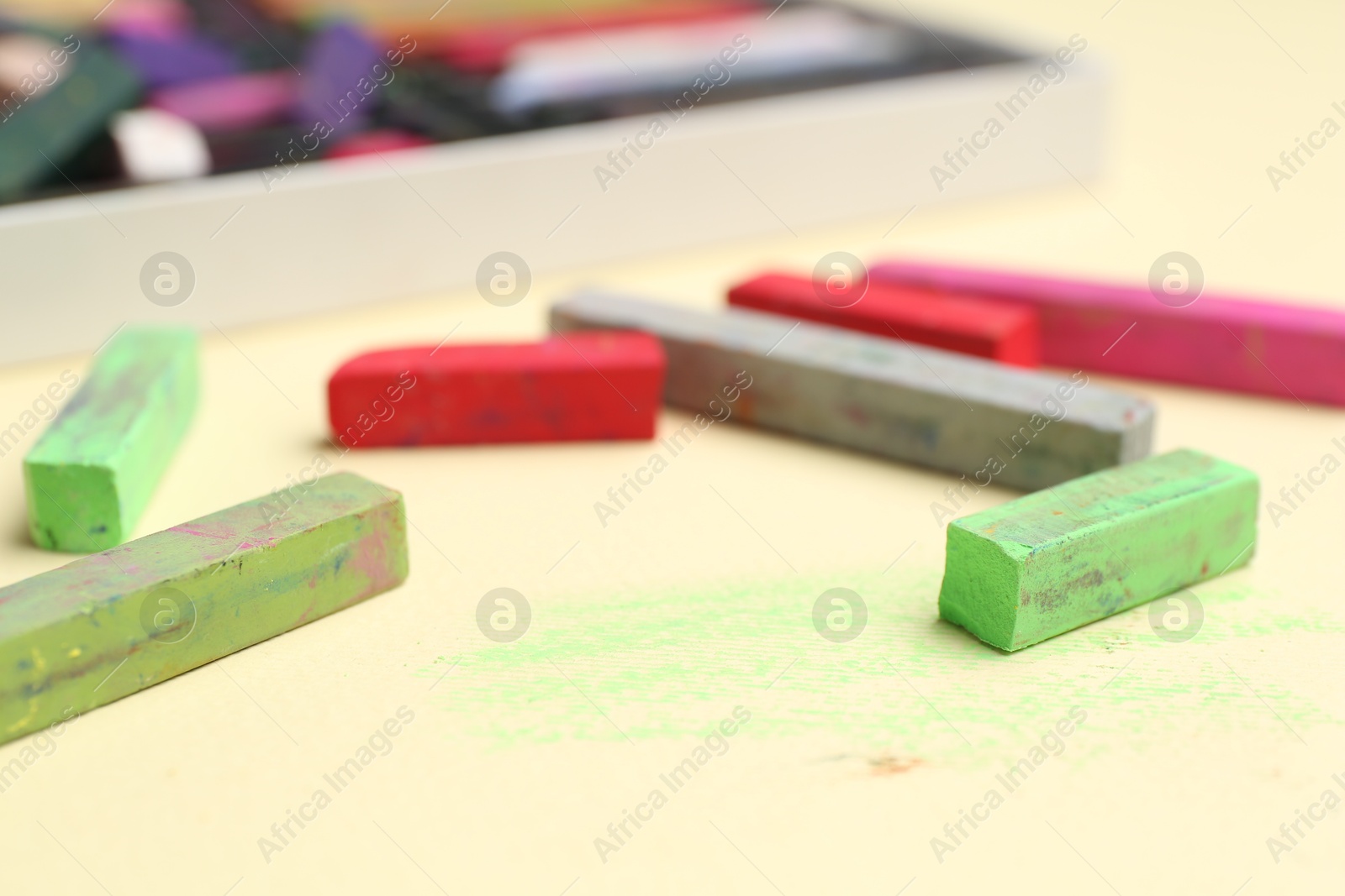 Photo of Many colorful chalk pastels on beige background, closeup