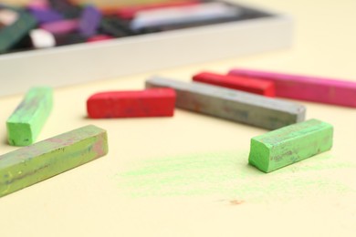 Photo of Many colorful chalk pastels on beige background, closeup