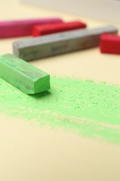 Photo of Many colorful chalk pastels on beige background, closeup