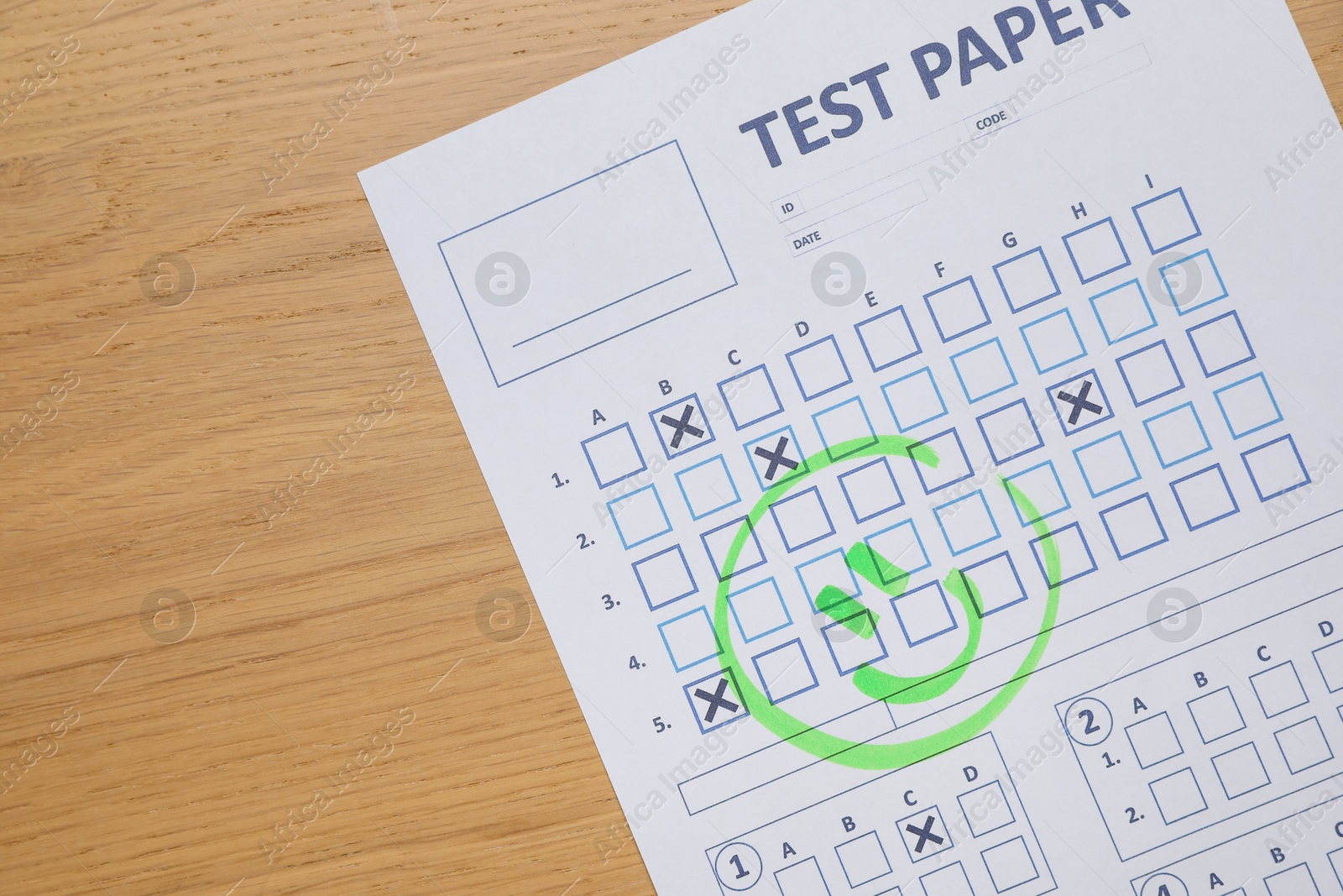 Photo of Answer sheet with drawn happy face on wooden table, top view. Student passing exam