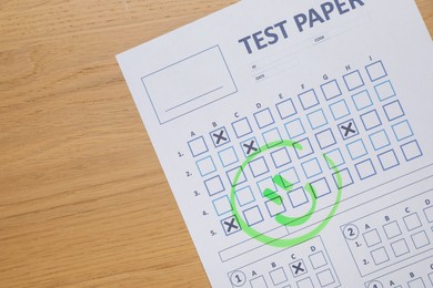 Photo of Answer sheet with drawn happy face on wooden table, top view. Student passing exam