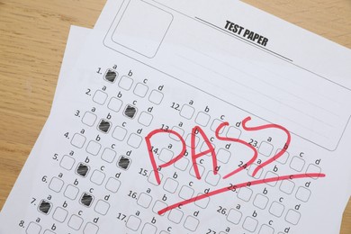 Photo of Answer sheet with word Pass on wooden table, top view. Student passing exam