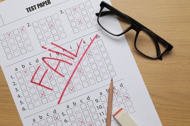 Photo of Answer sheet with word Fail, eraser, pencil and glasses on wooden table, flat lay. Student passing exam