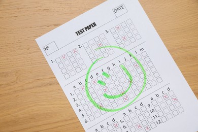 Photo of Answer sheet with drawn happy face on wooden table, top view. Student passing exam