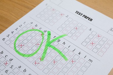 Photo of Answer sheet with word Ok on wooden table, closeup. Student passing exam