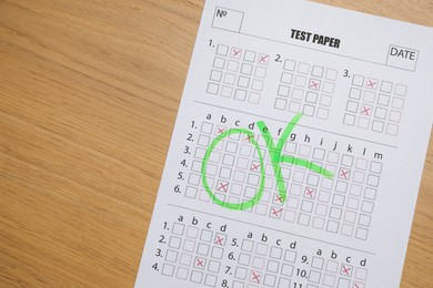 Photo of Student passing exam. Answer sheet with word Ok on wooden table, closeup. Space for text