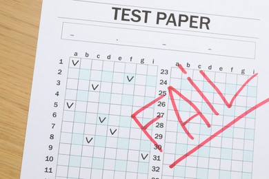Photo of Answer sheet with word Fail on wooden table, top view. Student passing exam