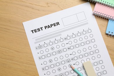 Photo of Answer sheet, eraser, pencil and notebooks on wooden table, flat lay. Student passing exam