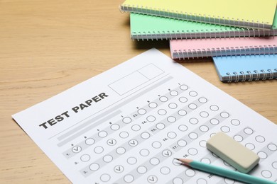 Photo of Answer sheet, eraser, pencil and notebooks on wooden table, closeup. Student passing exam